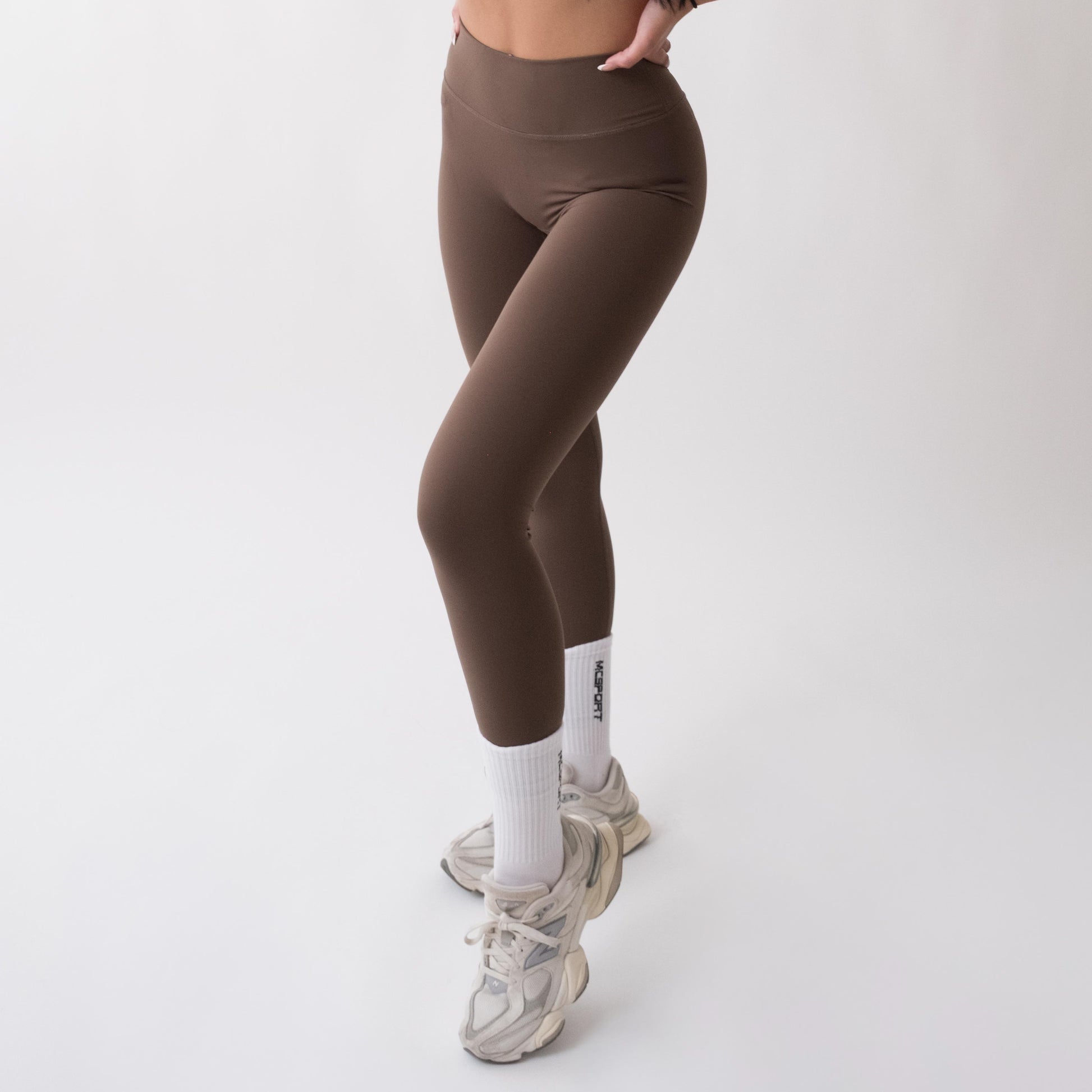 Leggings sportivi marroni da donna indossati a vita alta: tessuto elasticizzato, morbido e confortevole per fitness, yoga, pilates e allenamenti di ogni intensità.